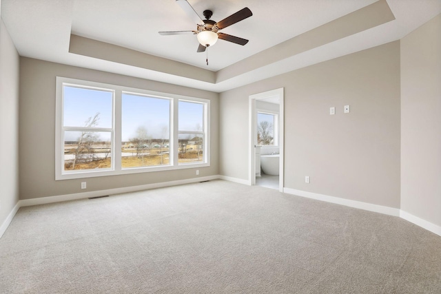 carpeted spare room featuring a tray ceiling and ceiling fan