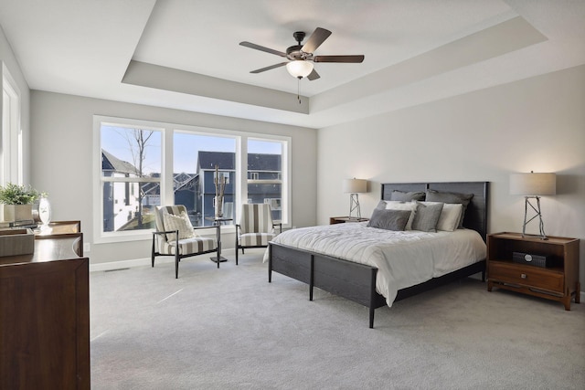 bedroom featuring a tray ceiling, ceiling fan, and light colored carpet