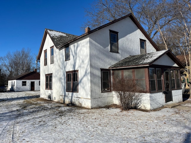 snow covered house featuring a sunroom