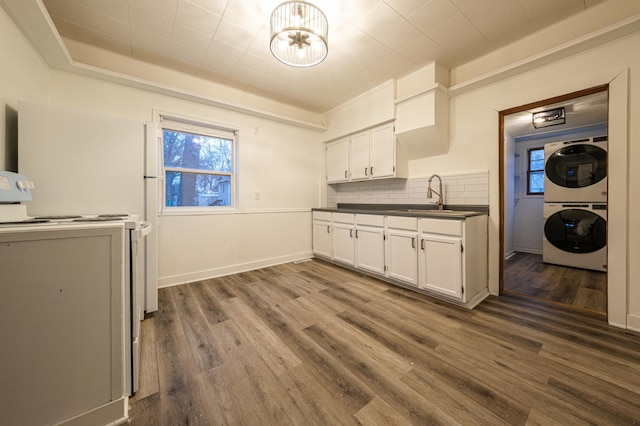 clothes washing area with hardwood / wood-style floors, stacked washer and clothes dryer, and sink