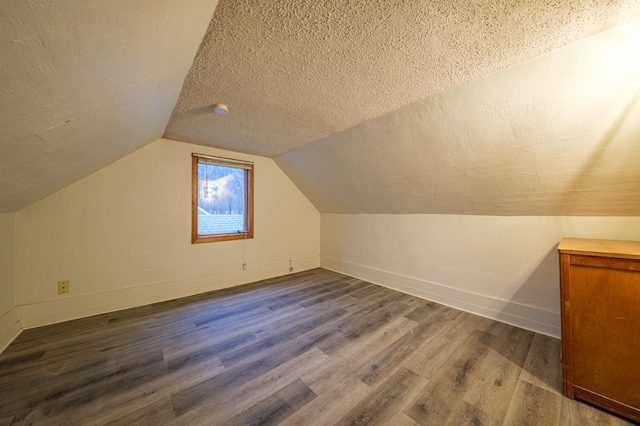 additional living space with a textured ceiling, hardwood / wood-style floors, and vaulted ceiling