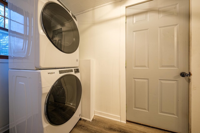 laundry room with dark hardwood / wood-style flooring and stacked washer / drying machine