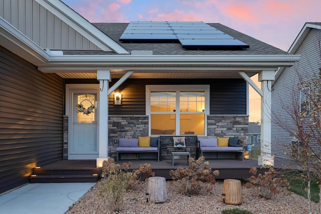 exterior entry at dusk with an outdoor hangout area and solar panels