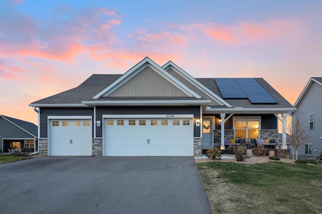 craftsman-style house with a garage, a lawn, and solar panels