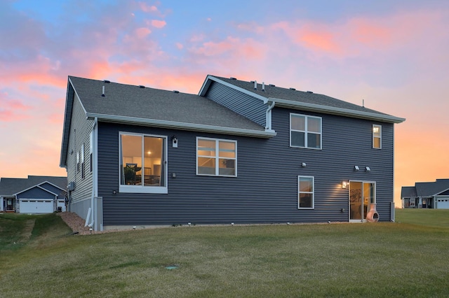 back house at dusk with a lawn