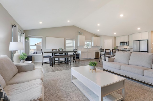 living room featuring vaulted ceiling, light hardwood / wood-style floors, and a wealth of natural light