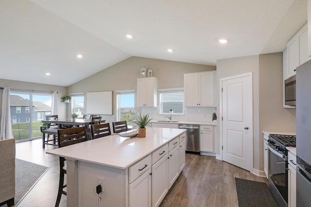 kitchen featuring sink, appliances with stainless steel finishes, white cabinetry, a kitchen island, and vaulted ceiling