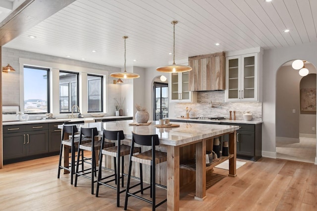 kitchen featuring pendant lighting, a center island, wooden ceiling, light wood-type flooring, and light stone counters