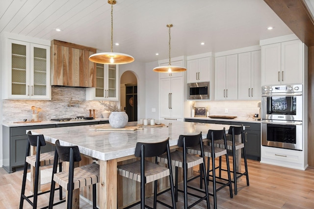 kitchen featuring pendant lighting, stainless steel appliances, white cabinetry, and a kitchen island