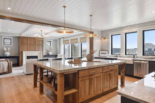 kitchen featuring dishwasher, sink, light stone counters, decorative light fixtures, and a fireplace