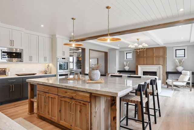 kitchen featuring pendant lighting, a center island, white cabinets, light hardwood / wood-style floors, and stainless steel appliances