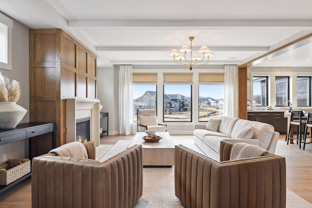 living room featuring light hardwood / wood-style floors, beam ceiling, and an inviting chandelier