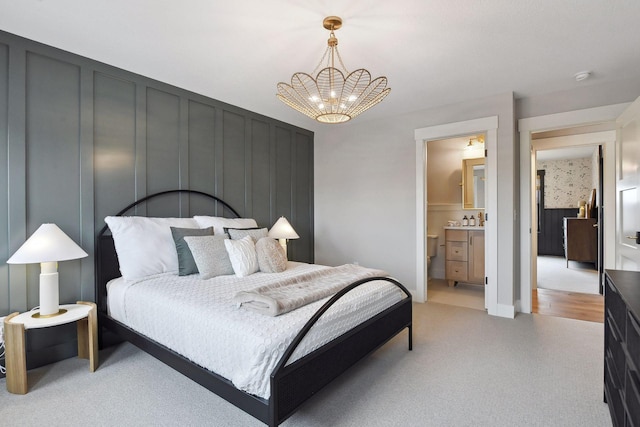 carpeted bedroom with ensuite bathroom, sink, and a chandelier