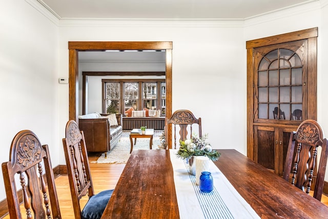 dining space featuring crown molding and light hardwood / wood-style flooring