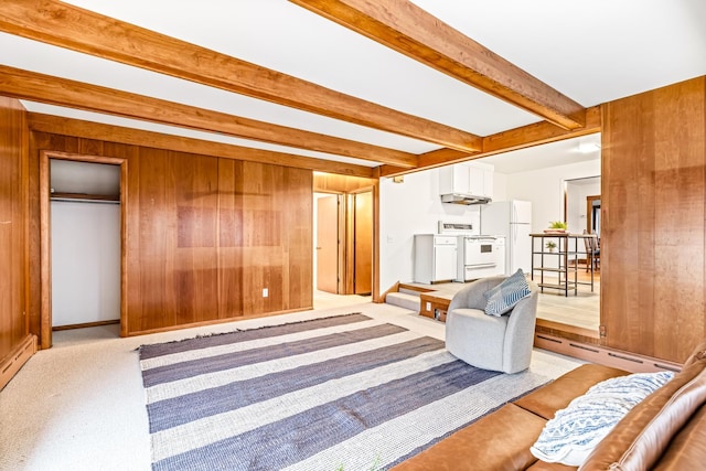 living area with beam ceiling, wood walls, light colored carpet, and a baseboard heating unit