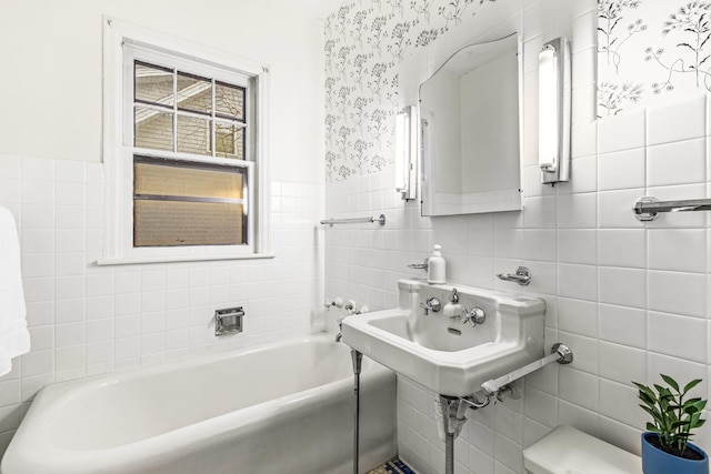 bathroom with a bathtub, sink, and tile walls