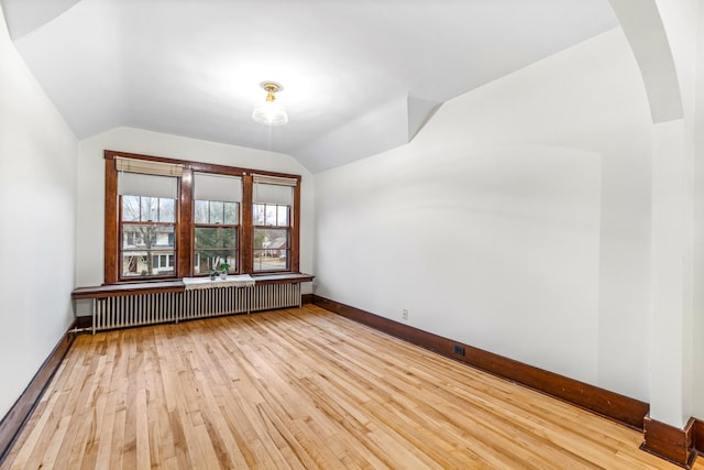 bonus room with radiator, light hardwood / wood-style flooring, and vaulted ceiling