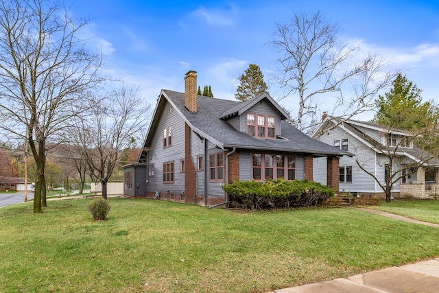 view of front of house featuring a chimney, a front lawn, a shingled roof, and brick siding