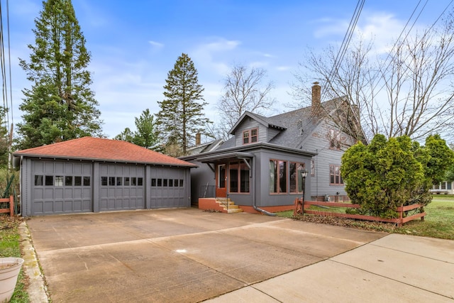 view of front of property with a detached garage, a chimney, an outdoor structure, and a shingled roof