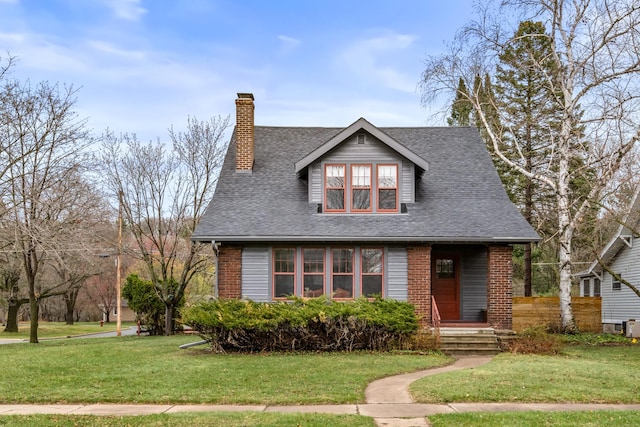 bungalow-style home with brick siding, a front lawn, roof with shingles, and a chimney