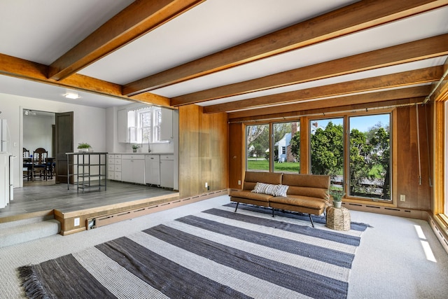 sitting room featuring beam ceiling, carpet, and wooden walls