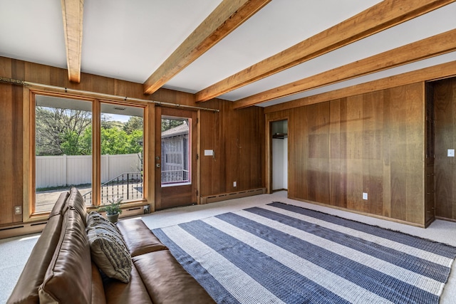 unfurnished living room featuring a baseboard heating unit, beam ceiling, wood walls, and carpet floors