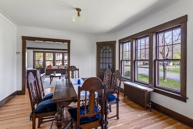 dining room featuring radiator heating unit, light wood-style flooring, baseboards, and crown molding
