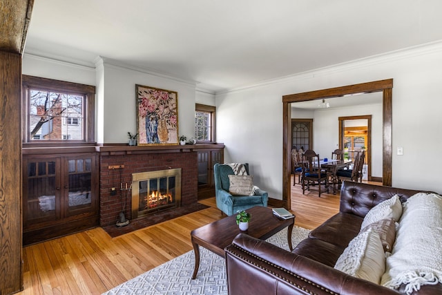 living area featuring plenty of natural light, crown molding, wood finished floors, a fireplace, and baseboards