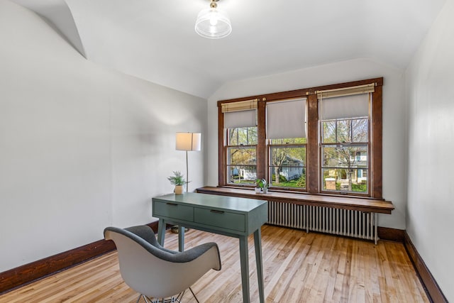office area featuring radiator heating unit, vaulted ceiling, light wood finished floors, and baseboards