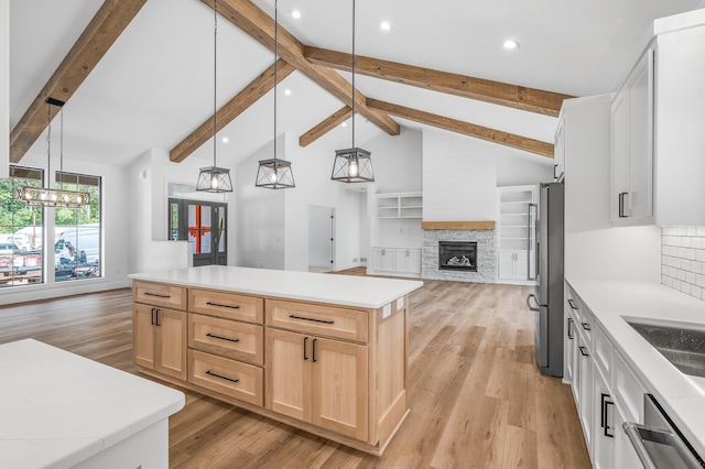 kitchen featuring beam ceiling, a center island, stainless steel fridge, pendant lighting, and white cabinets