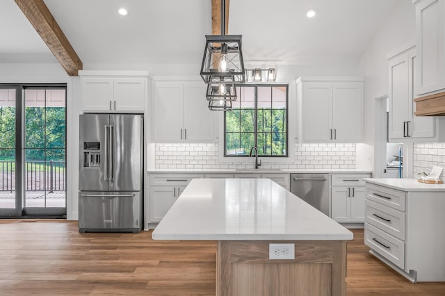 kitchen with white cabinets, decorative backsplash, stainless steel appliances, and a kitchen island