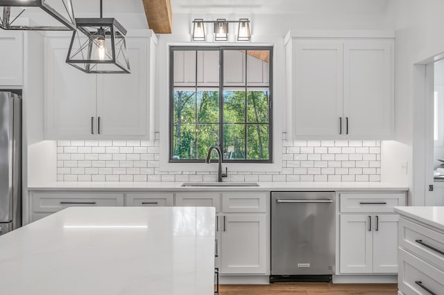 kitchen with pendant lighting, white cabinets, sink, and stainless steel appliances