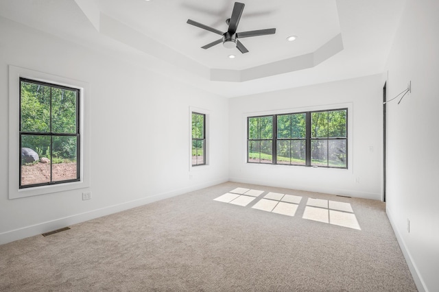 carpeted spare room featuring ceiling fan and a tray ceiling