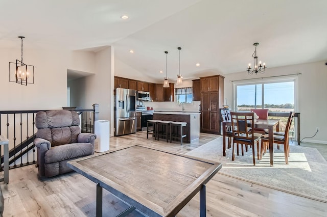 living room with sink, light hardwood / wood-style flooring, lofted ceiling, and a notable chandelier