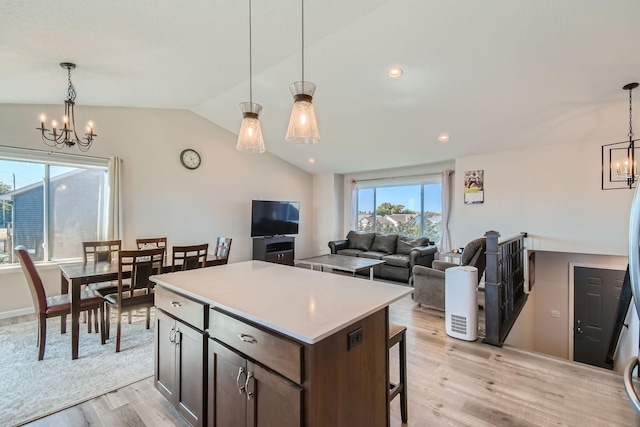 kitchen with a center island, hanging light fixtures, a notable chandelier, vaulted ceiling, and light wood-type flooring