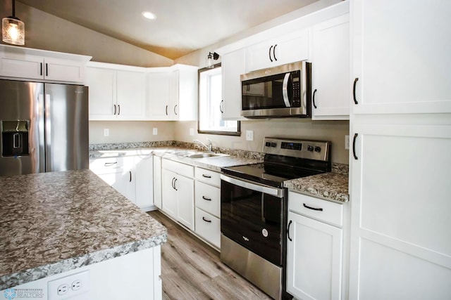 kitchen with sink, hanging light fixtures, lofted ceiling, white cabinets, and appliances with stainless steel finishes