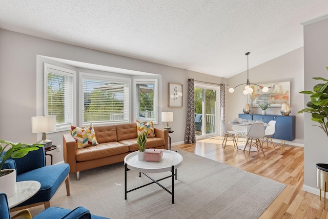 living area with a textured ceiling, baseboards, wood finished floors, and lofted ceiling