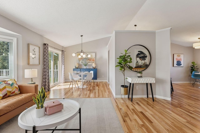 living area featuring light wood-style floors, baseboards, lofted ceiling, and a notable chandelier