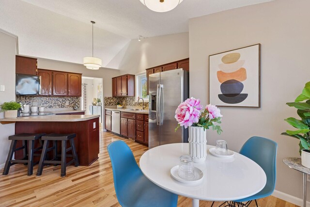 dining area featuring lofted ceiling and light wood-type flooring