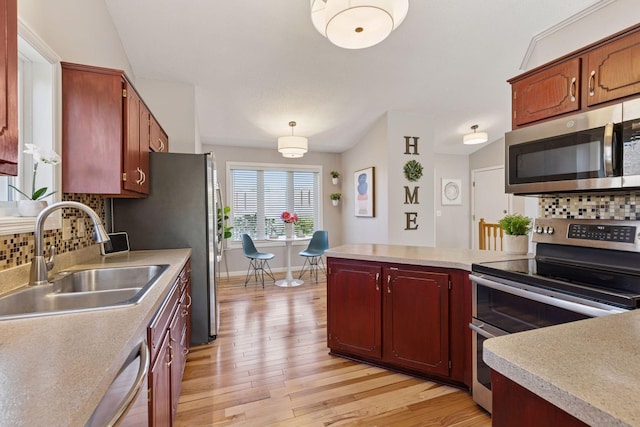 kitchen featuring a sink, stainless steel appliances, light countertops, and light wood-style floors