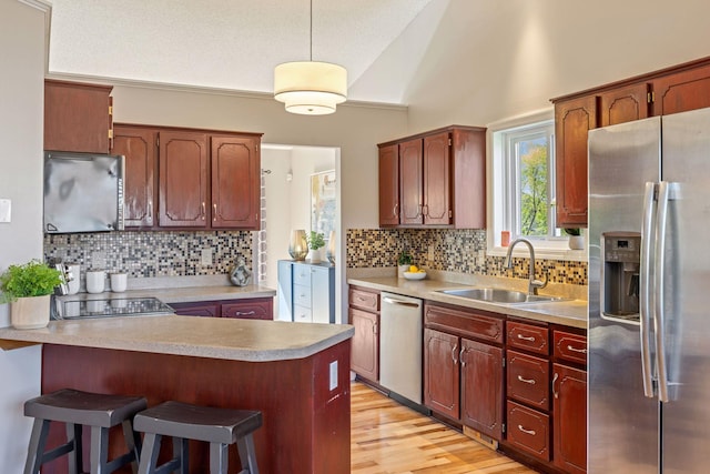 kitchen featuring a sink, a peninsula, decorative backsplash, light countertops, and appliances with stainless steel finishes