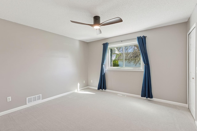 unfurnished room with carpet, visible vents, baseboards, and a ceiling fan