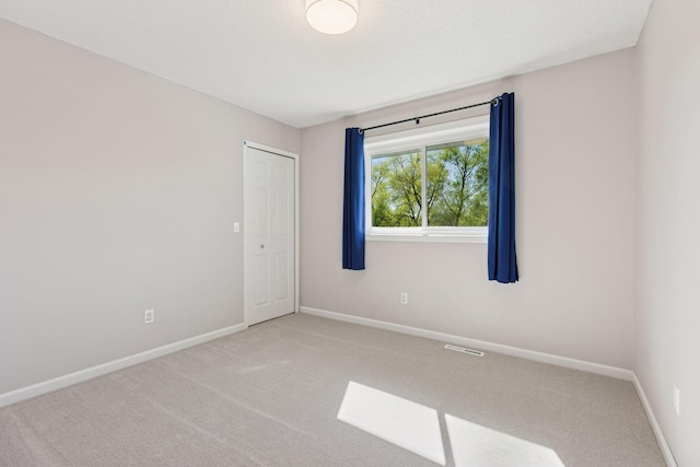 carpeted spare room with visible vents and baseboards
