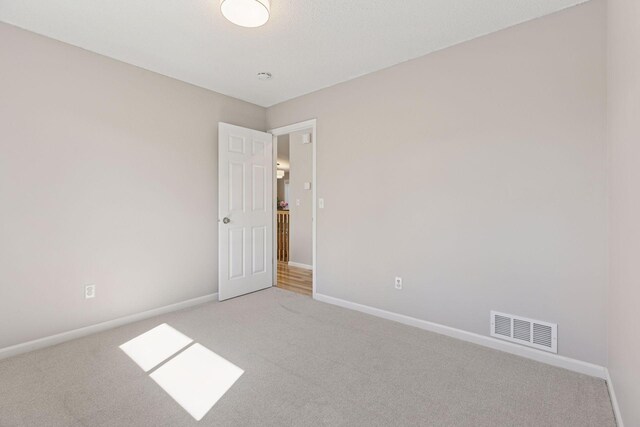 empty room featuring carpet floors, baseboards, and visible vents