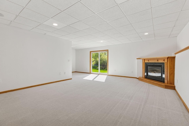 unfurnished living room featuring a paneled ceiling, baseboards, a glass covered fireplace, and light colored carpet