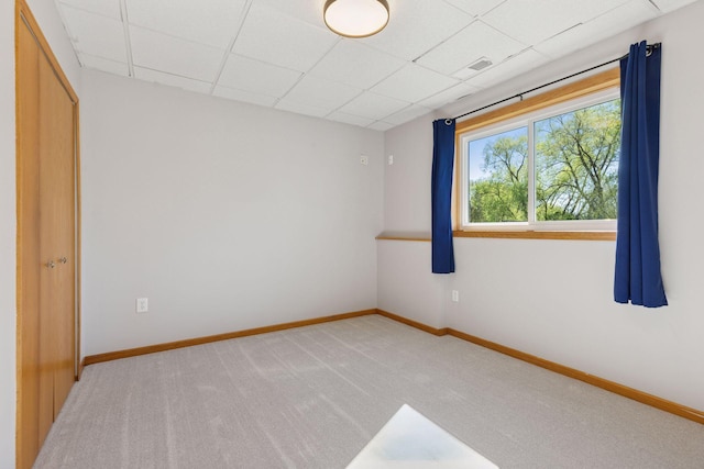 carpeted empty room with visible vents, baseboards, and a paneled ceiling