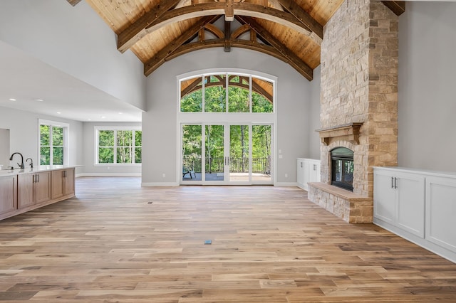 unfurnished living room with a fireplace, light wood-type flooring, high vaulted ceiling, and wood ceiling