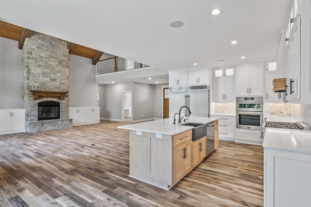 kitchen with sink, wood-type flooring, a center island with sink, white cabinets, and appliances with stainless steel finishes