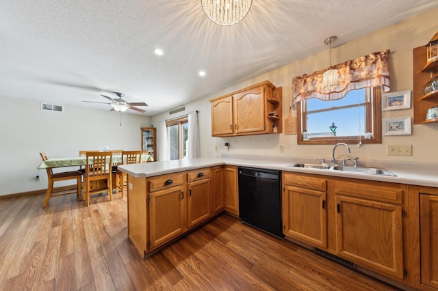 kitchen featuring pendant lighting, a textured ceiling, dishwasher, sink, and kitchen peninsula