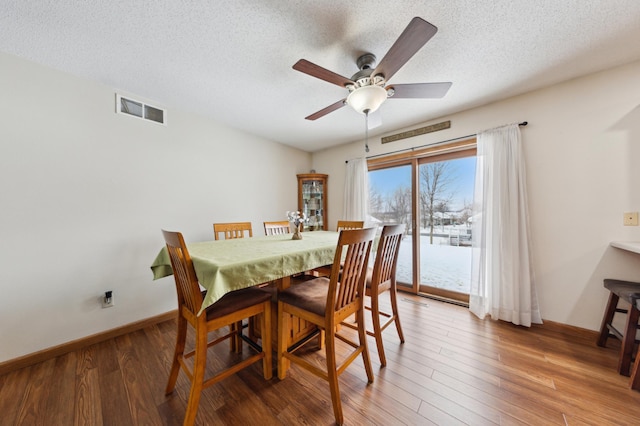 dining area featuring ceiling fan, wood-type flooring, and a textured ceiling